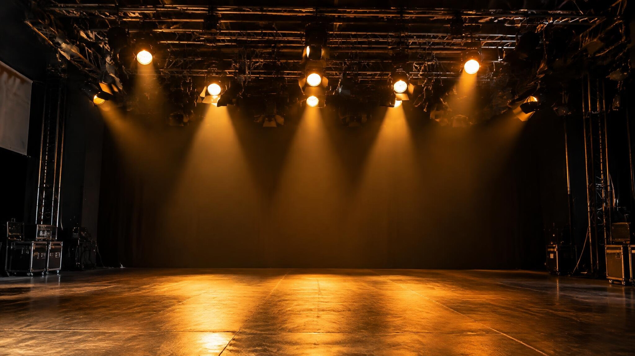 Stage lighting rig glowing above a studio floor